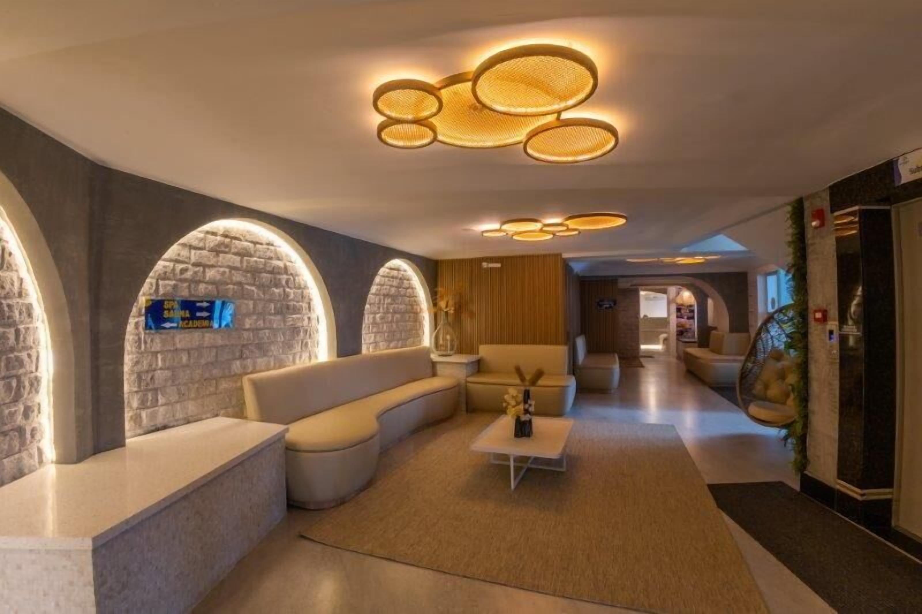 A modern hotel lobby with a reception desk, seating areas, and a unique ceiling design.
