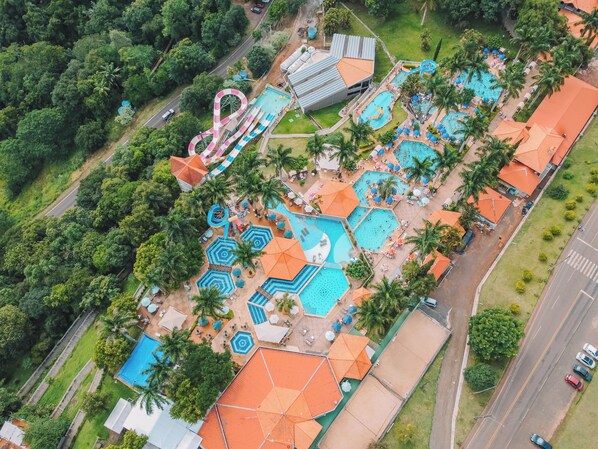 Vista aérea de un complejo turístico con múltiples piscinas, un tobogán acuático y un estacionamiento.