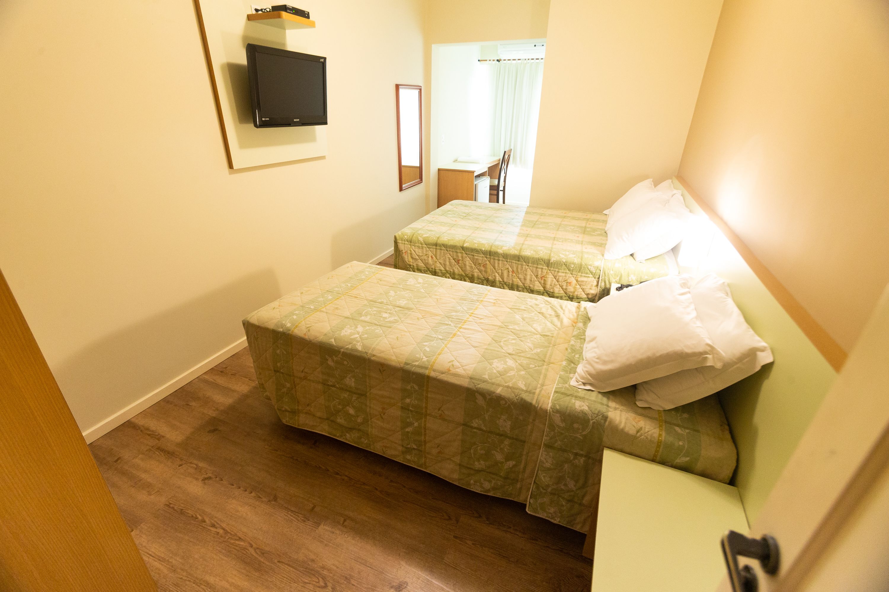 A room with two beds, a desk, and a television.