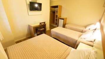 Una habitación de hotel con dos camas, un escritorio, una silla, un armario y un televisor.