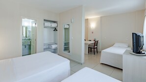 A hotel room with two beds, a desk, a chair, a TV, and a closet with hanging clothes.