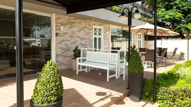 An outdoor patio area with a white bench, potted plants, and outdoor furniture.