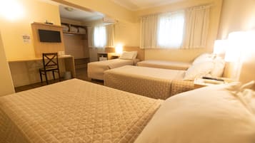 Ein Hotelzimmer mit zwei Betten, einem Schreibtisch, einem Sessel und einem Fernseher.