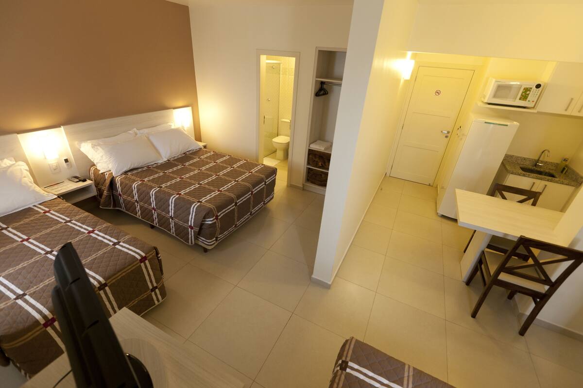 Ein Hotelzimmer mit zwei Betten, einer Küchenzeile und einem Badezimmer.