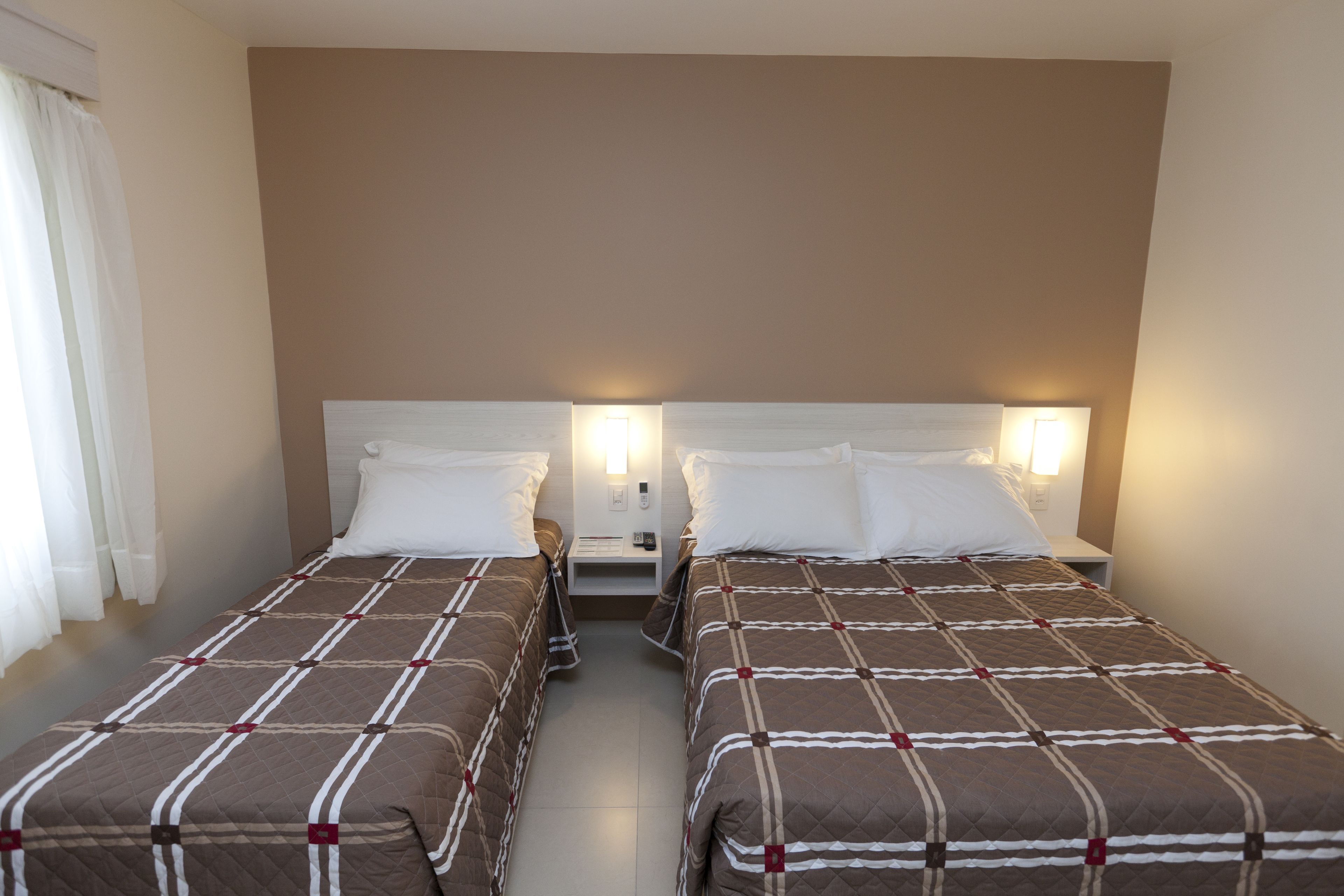 Une chambre double avec deux lits, chacun doté d’une tête de lit, de tables de chevet et de lampes.