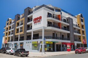 A multi-story hotel with a prominent red sign, multiple balconies, and a ground-level storefront. - Flipper Hotel (Laguna)