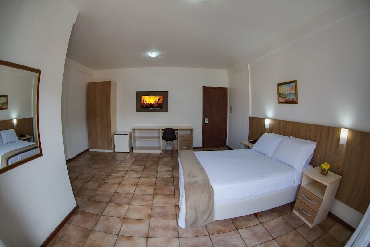 Quarto com cama, escrivaninha, cadeira e guarda-roupa.