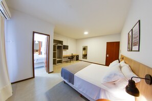 A hotel room with a bed, bedside table, lamp, wardrobe, and a desk with chair. - Flipper Hotel (Laguna)