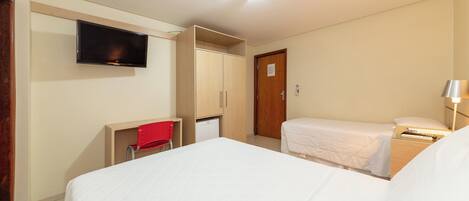 Habitación de hotel con dos camas, un televisor, un escritorio y un armario.