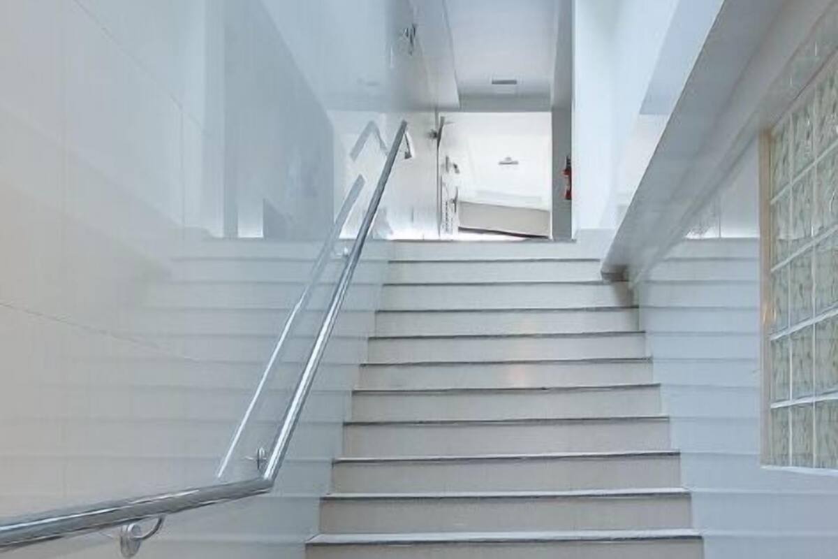 A staircase with a metal handrail leading to a landing with a door and a light fixture.