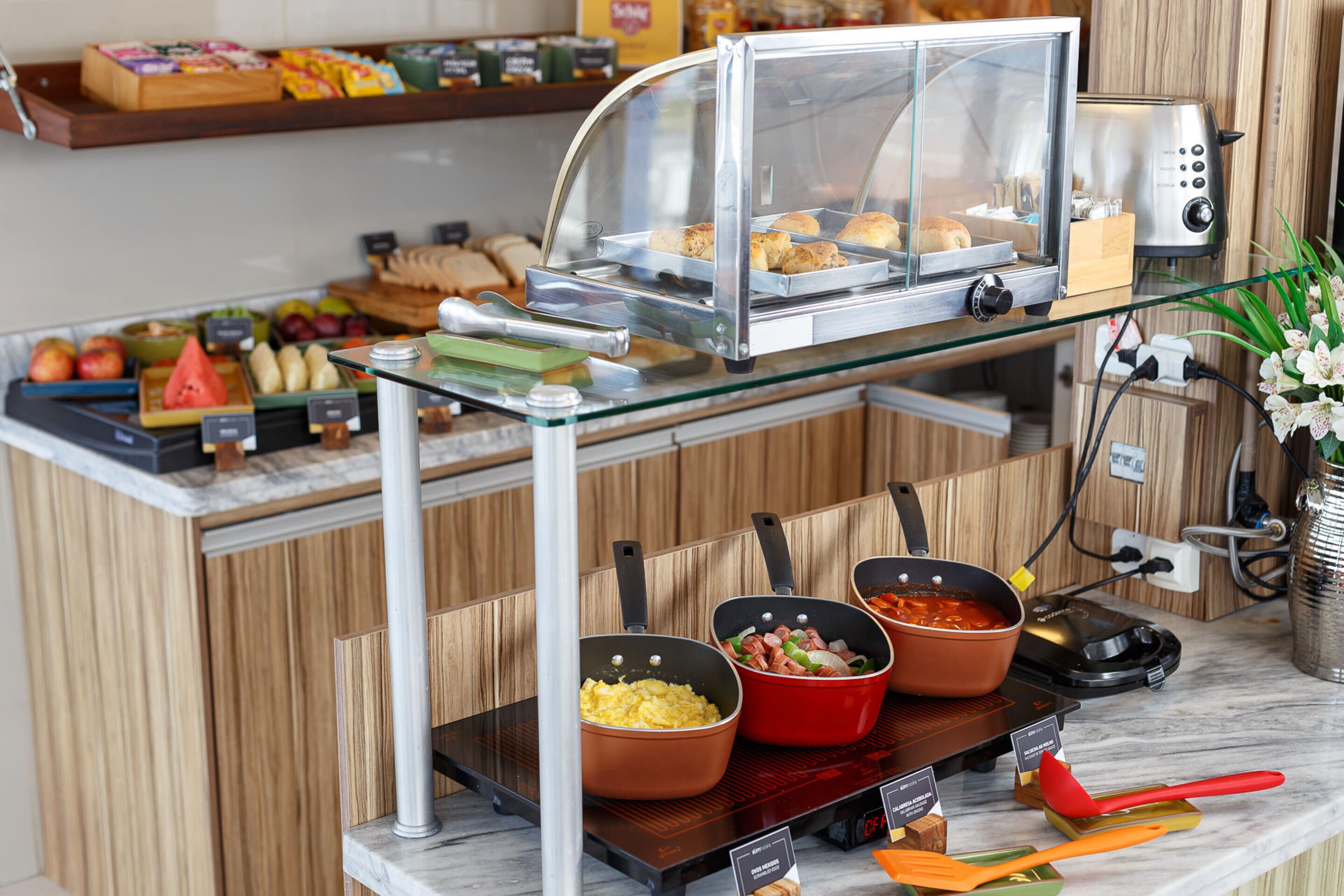 Disposição de buffet com diversos alimentos e equipamentos de cozinha.