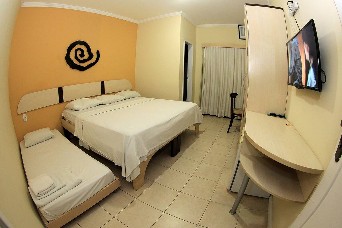 Una habitación de hotel con una cama, un escritorio y una televisión.