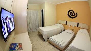 A hotel room with two single beds, a television on the left, and a door leading to a bathroom.