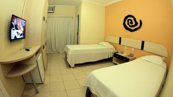 A hotel room with two beds, a desk, a television, and a wall with a logo.