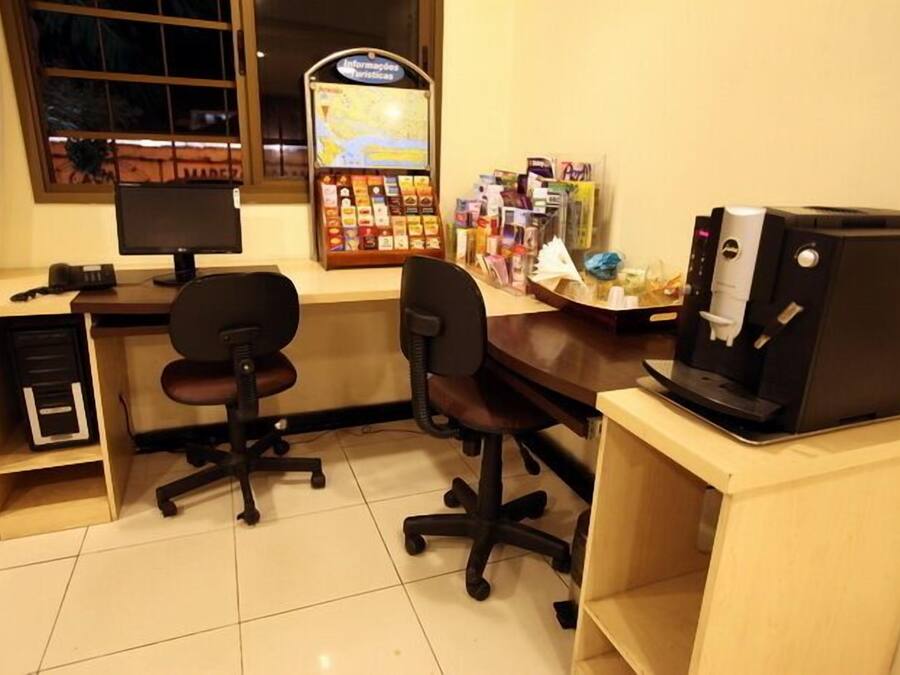 A small office with two black office chairs, a desk with a computer, a printer, and a map display.