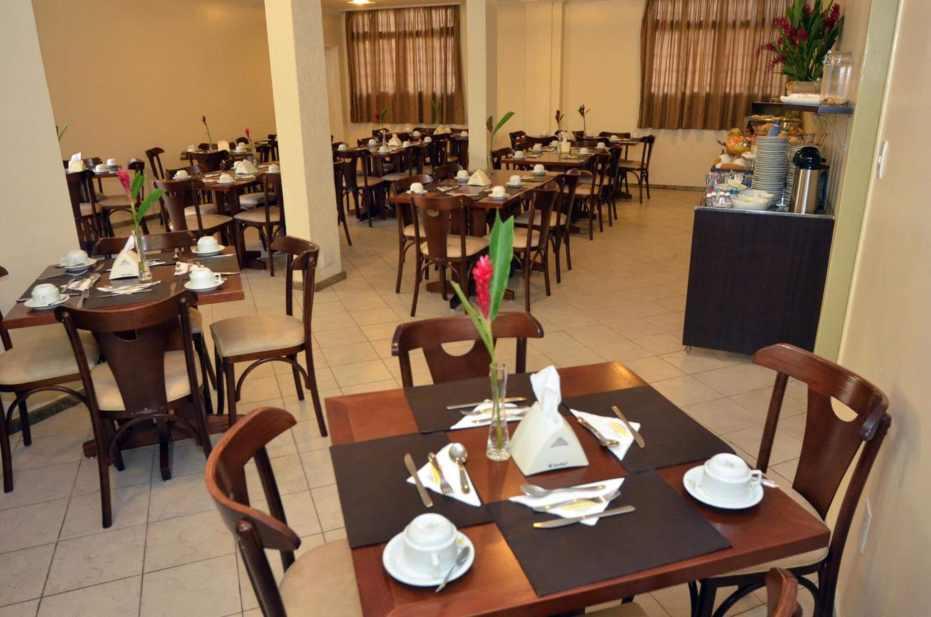 Un comedor con varias mesas y sillas, dispuesto en un espacio amplio.