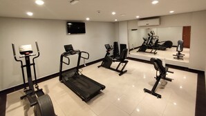 Ein Fitnessraum mit Cardiogeräten, Kurzhanteln und einer Spiegelwand.