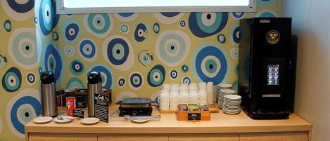 Una estación de café con cafetera, tazas y máquina de café.