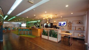Eine moderne Hotelhalle mit Empfangstresen, Barbereich und Sitzgelegenheiten.