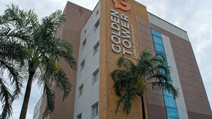 Ein Hotel namens "Golden Tower Express Arapaqua" mit auffälliger Beschilderung, umgeben von Palmen.
