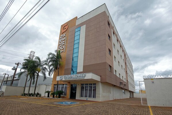 A multi-story hotel with a prominent 'Golden Tower' sign, a ground-level 'Golden Tower Express Araraquara' entrance, and a parking area with a disabled parking space. - Golden Tower Express Araraquara by Fênix Hotéis (Araraquara)