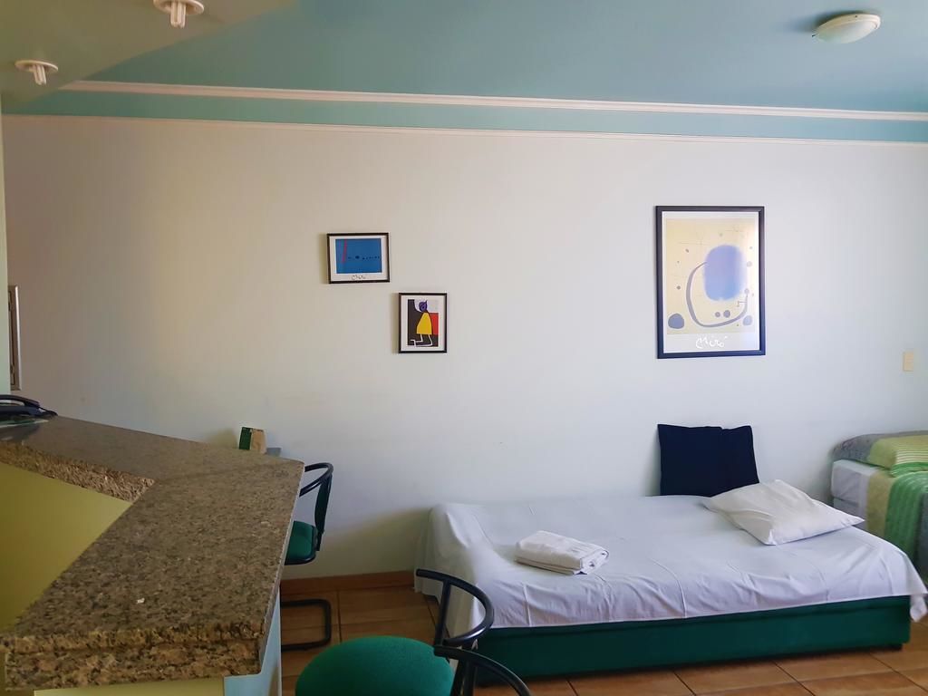 A room with a bed, a chair, a desk, and a wall with two framed pictures.