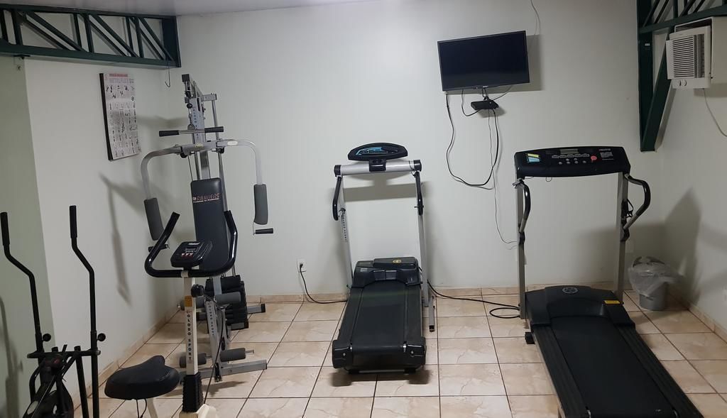 A home gym with a treadmill, elliptical, and weight machine.