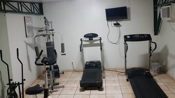 A home gym with a treadmill, elliptical, and weight machine.