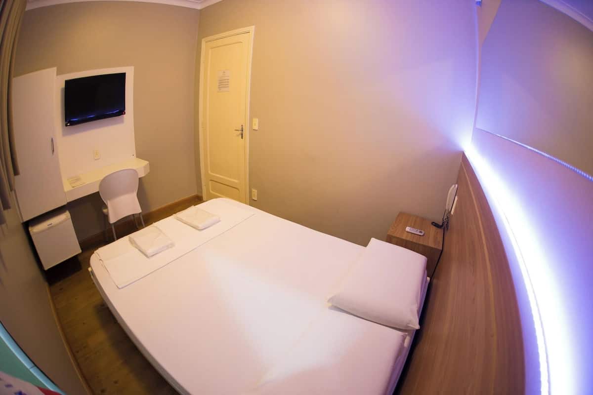Ein Hotelzimmer mit Bett, Schreibtisch, Stuhl, Fernseher und einer Tür.
