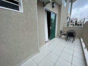 A balcony with a tiled floor, a green door, and a small table with chairs. - The Green Ecologic Hotel (Guarujá)