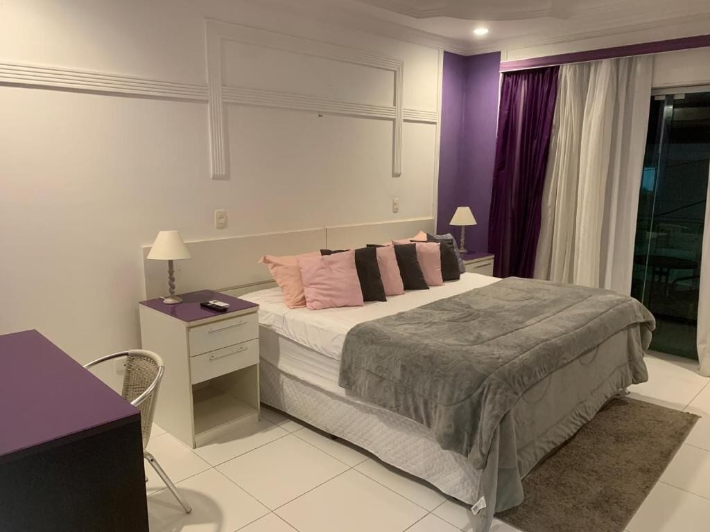 A bedroom with a bed, nightstands, a desk, and a chair.