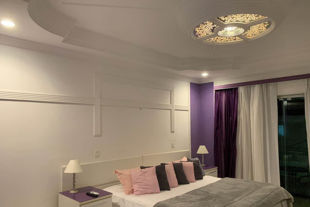A bedroom with a bed, nightstand, lamp, and a ceiling light fixture.