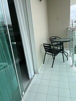 Un balcon avec une porte-fenêtre, une petite table ronde et deux chaises.