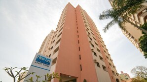 Un edificio alto de color rosa con un letrero que dice 'New Life Piracicaba Apart Hotel'.