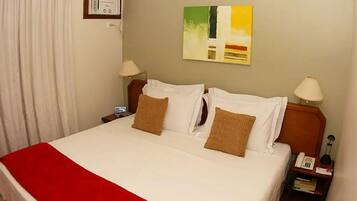 Una camera d'albergo con un letto grande, due comodini, una lampada e un quadro appeso al muro.