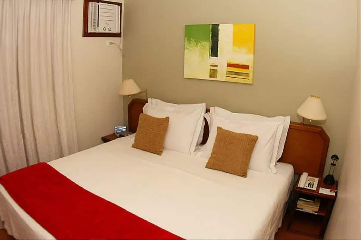 A hotel room with a large bed, two bedside tables, a lamp, and a painting on the wall.