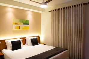 A hotel room with a bed, a ceiling fan, a wall-mounted light, and a window with vertical blinds. - New Life Piracicaba (Piracicaba)