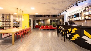 Un interior moderno con una mesa de comedor de madera, sillas rojas, un sofá rojo y una zona de bar con diseño negro y amarillo.