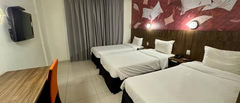 A hotel room with two beds, a desk, and a TV.