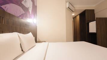 A hotel room with a large bed, a wooden headboard, a wall-mounted air conditioner, and a wardrobe.