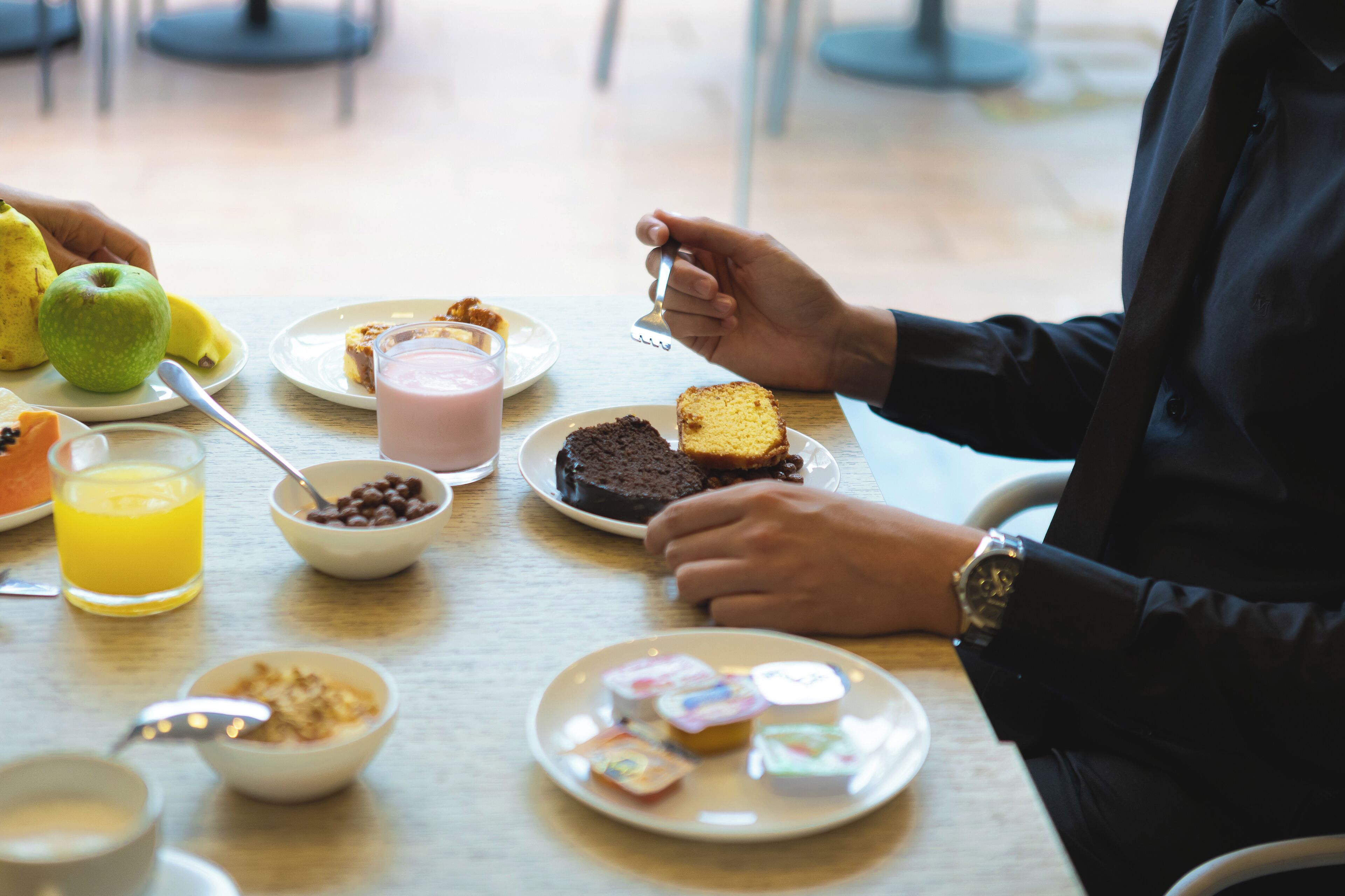 A breakfast table with various food items and a person eating.