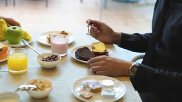 Una mesa de desayuno con diferentes alimentos y una persona comiendo.