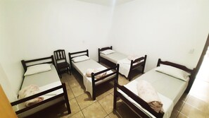 Un dormitorio con cuatro camas individuales, una mesita y una silla.