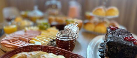 A buffet with various food items including sliced meats, pastries, and a chocolate dessert.