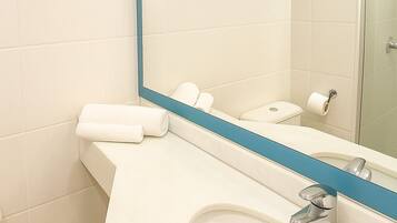 A bathroom with a white sink, a mirror with a blue frame, and a toilet.