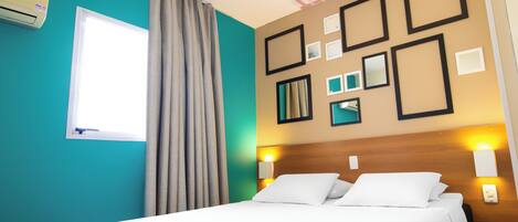 A hotel room with a bed, curtains, a window, wall-mounted lights, and framed pictures.
