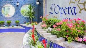 A tiled pool area with a sign reading "L'Opera Hotel".