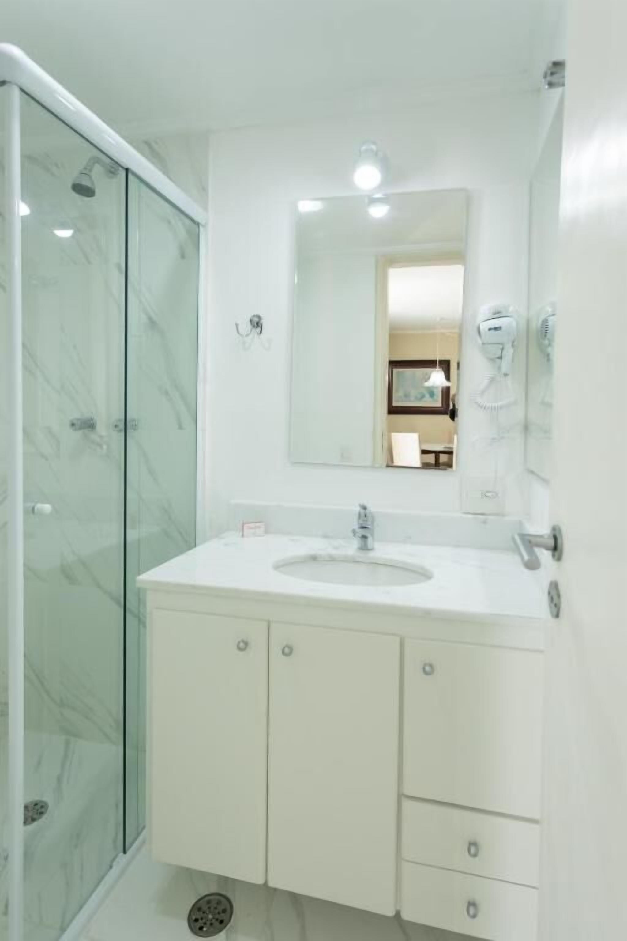 A modern bathroom with a glass shower enclosure, a white sink, and a large mirror.