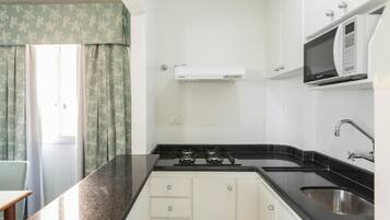 A compact kitchen with a gas stove, a microwave, and a sink.