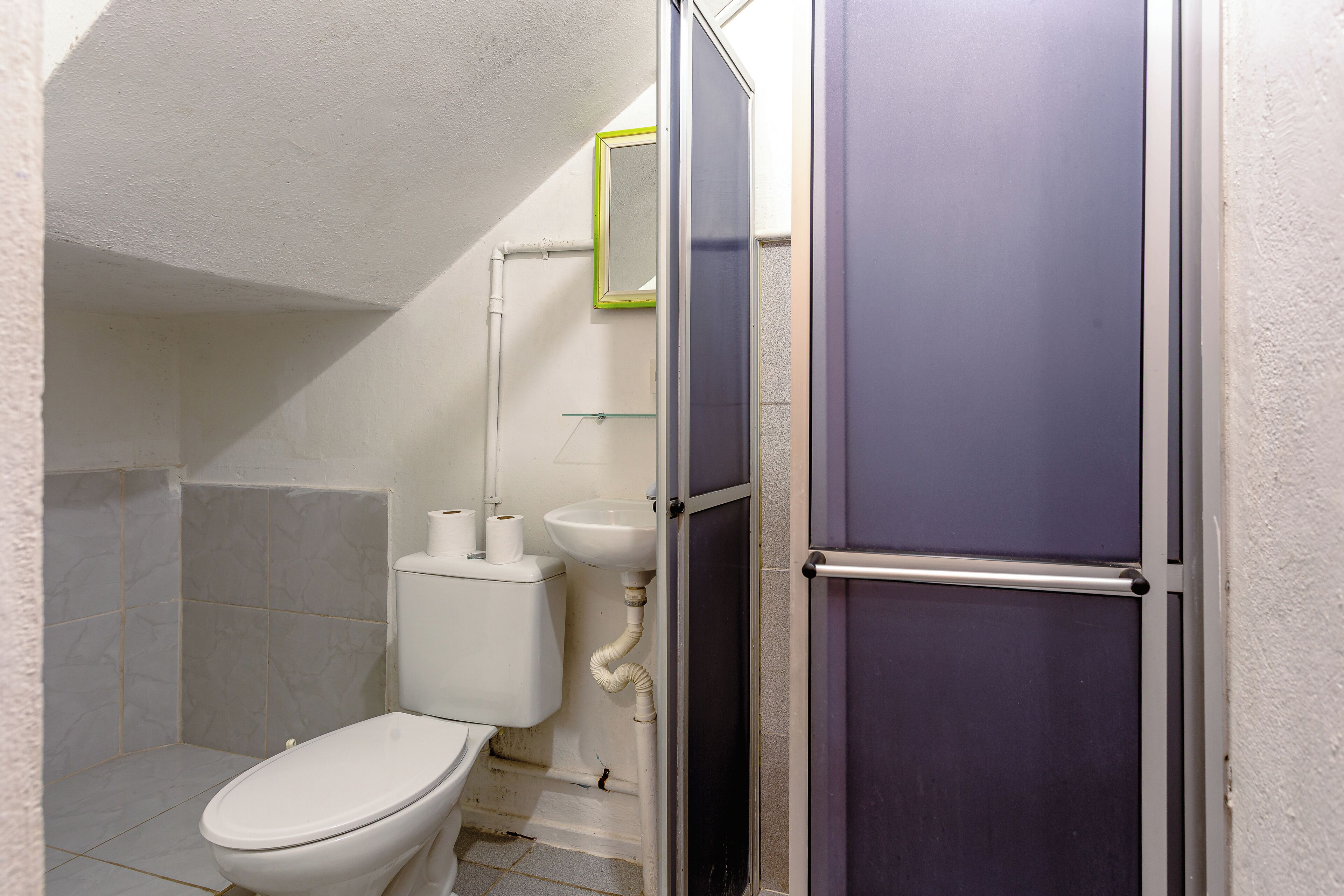 A small bathroom with a toilet, sink, and shower.